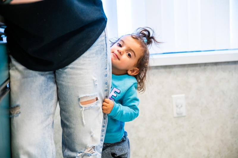 a girl hiding behind her mom