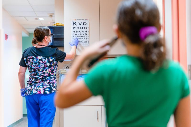 a girl covering her left eye while taking an eye exam
