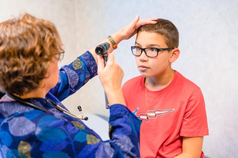 a boy in glasses getting his eyes examined