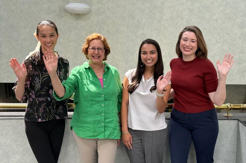 four women smiling and waving