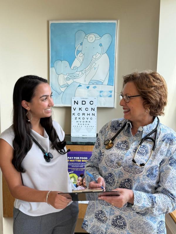 two medical professionals exchanging a clipboard